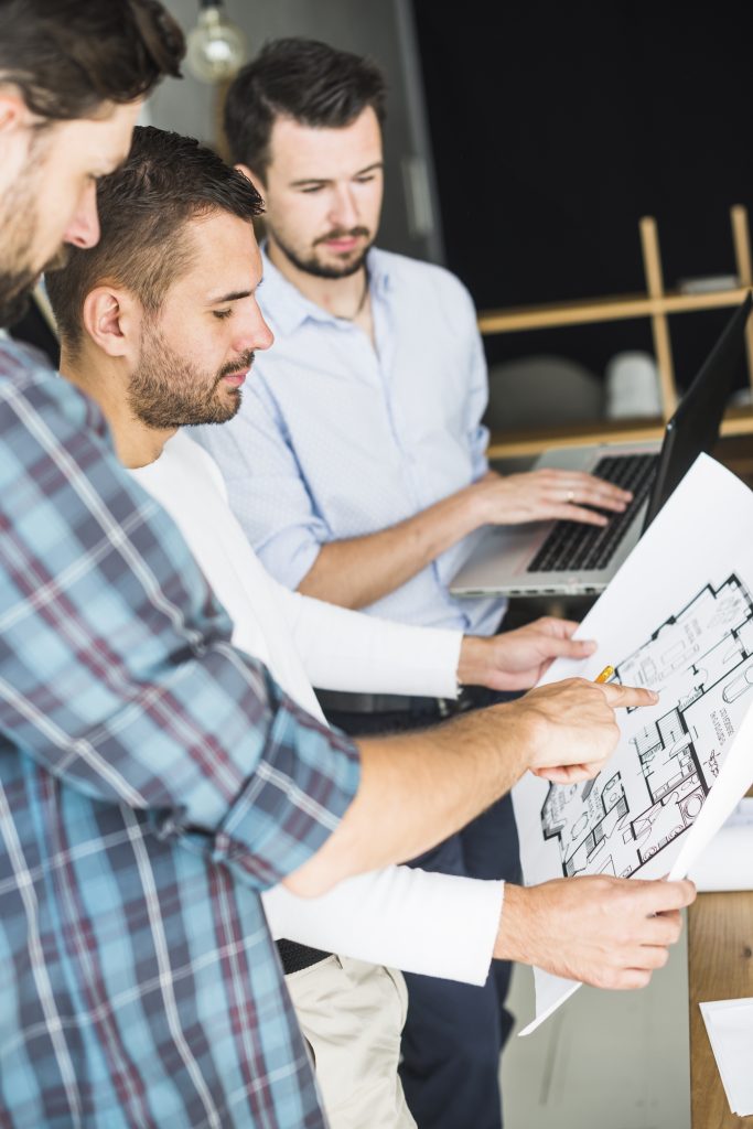 architects analyzing a blueprint and using BIM consulting services on laptop
